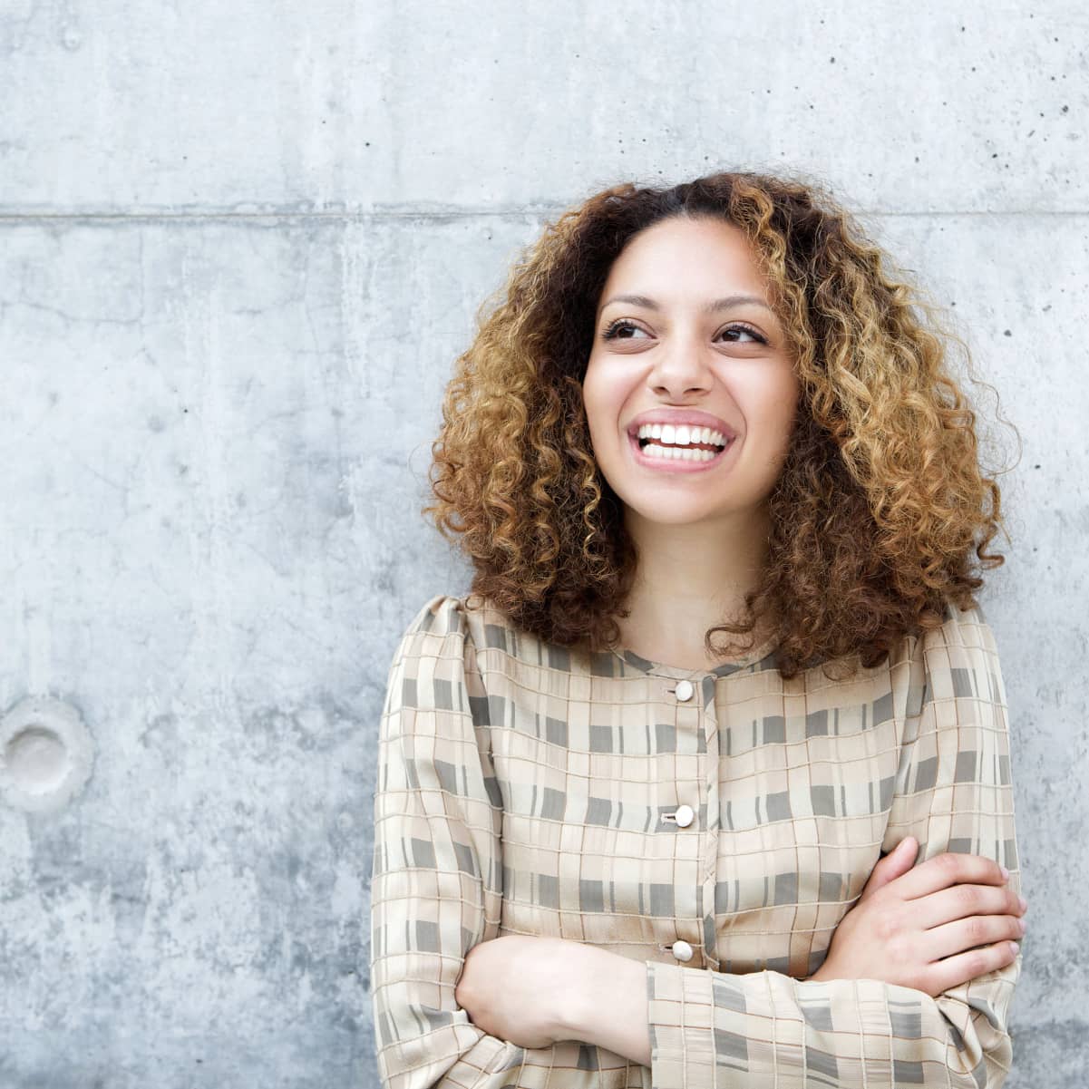 woman-smiling-outdoors-with-arms-crossed-PQRAJJK-min cropped