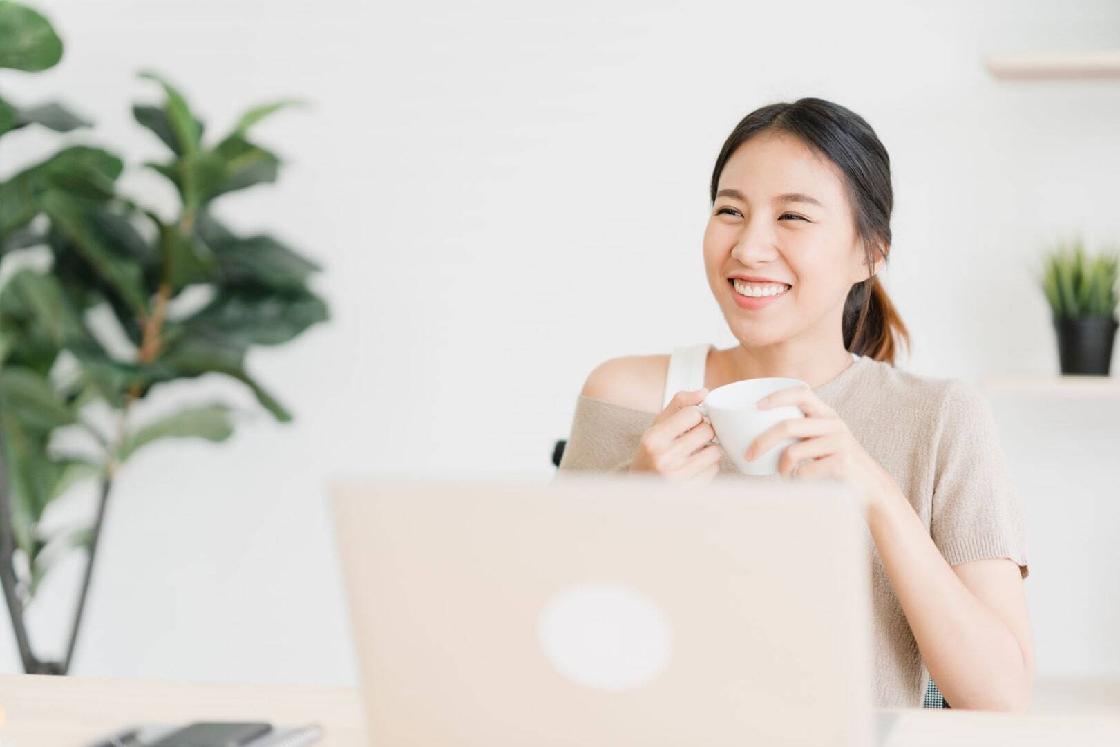 beautiful-young-smiling-asian-woman-working-laptop-drinking-coffee