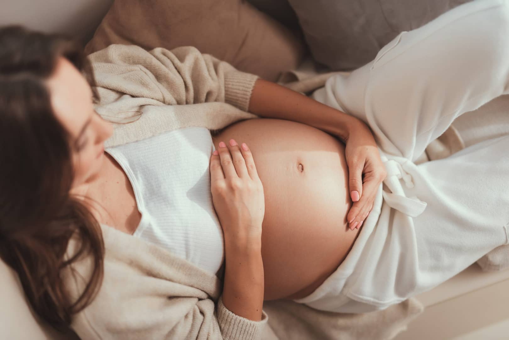 surrogate holding baby belly on couch