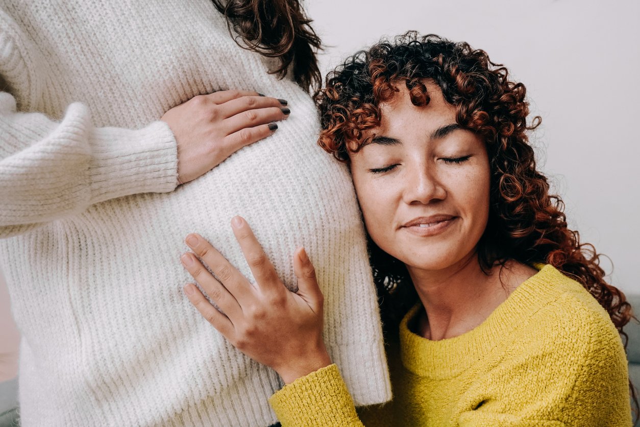 curly hair woman holding surrogate pregnant belly